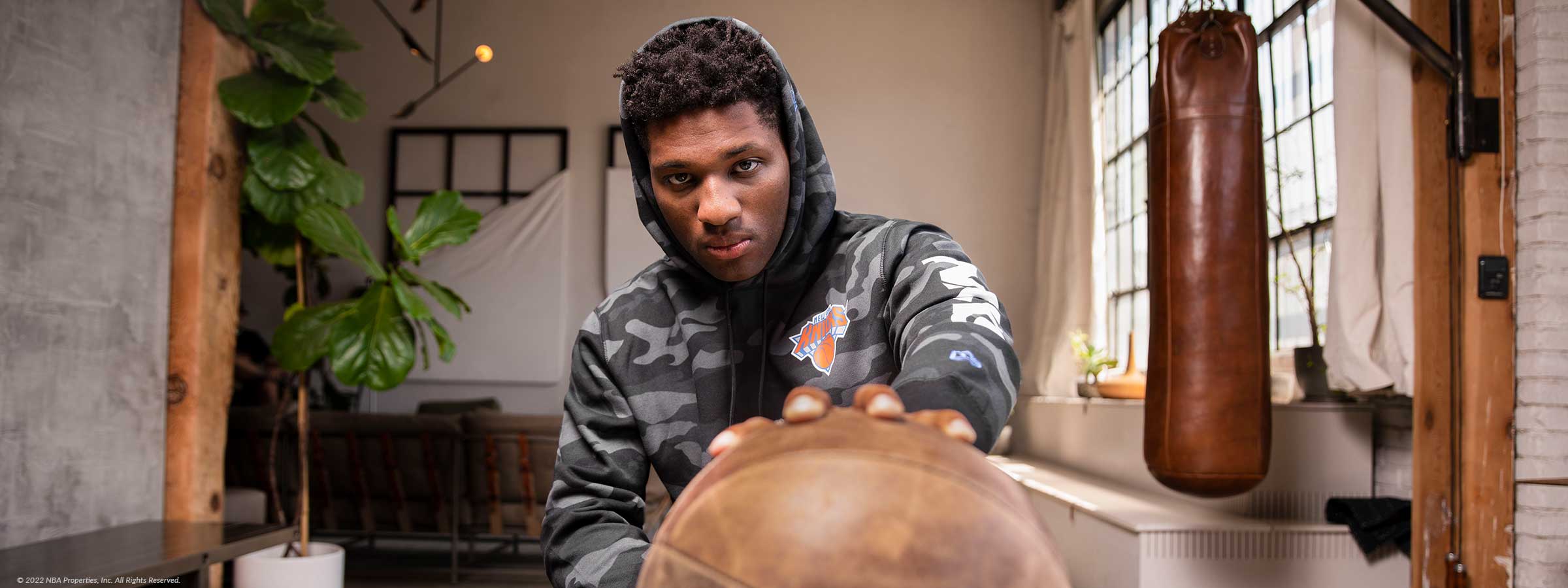 Man holding basketball in NBA Lifestyle Camo hoodie